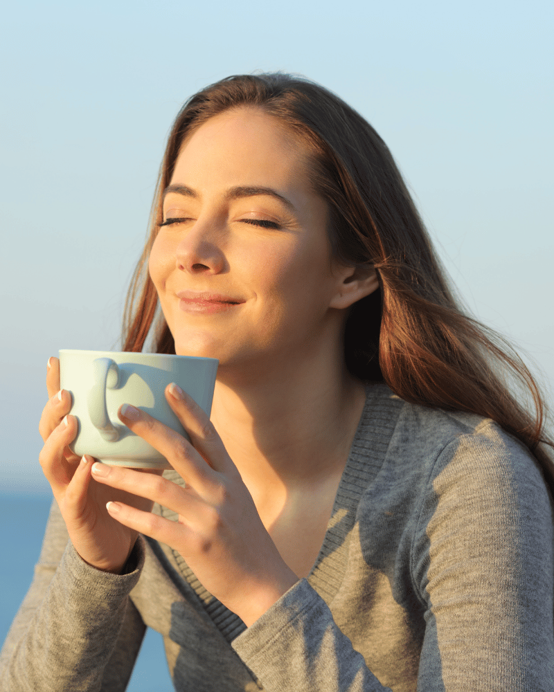 Person enjoying a warm cup of CBD coffee in the morning